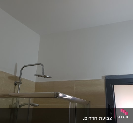 קיר צבוע בלבן מעל מקלחון בחדר אמבטיה